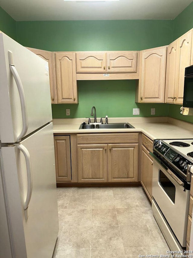 kitchen featuring light tile patterned flooring, sink, stove, and white fridge