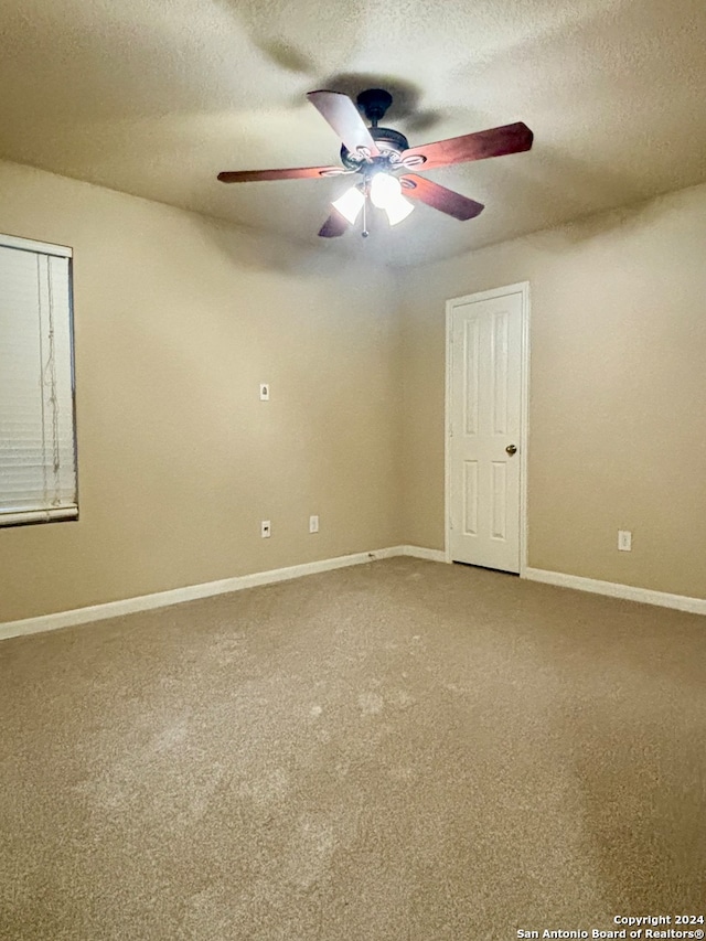 spare room featuring ceiling fan, a textured ceiling, and carpet