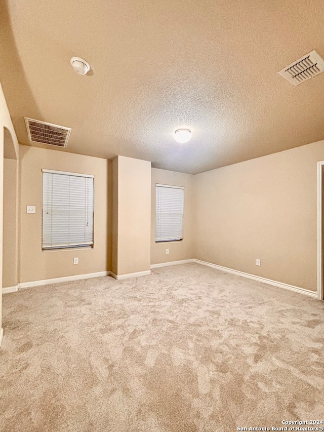 carpeted spare room with a textured ceiling