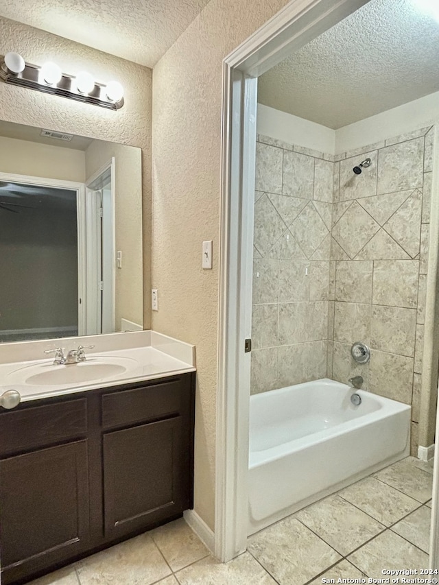 bathroom featuring tiled shower / bath, a textured ceiling, tile patterned floors, and vanity