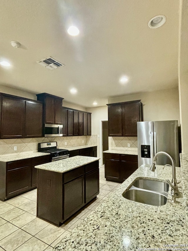 kitchen featuring sink, a center island, appliances with stainless steel finishes, dark brown cabinetry, and tasteful backsplash