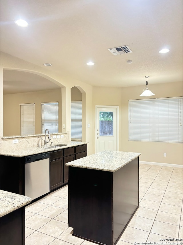 kitchen featuring sink, hanging light fixtures, stainless steel dishwasher, and light tile patterned floors