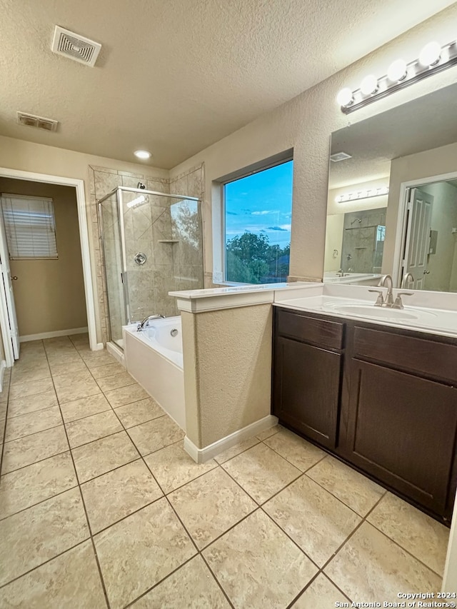 bathroom with a textured ceiling, tile patterned flooring, shower with separate bathtub, and vanity