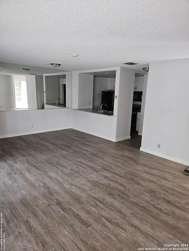 unfurnished living room featuring hardwood / wood-style flooring, a textured ceiling, and sink