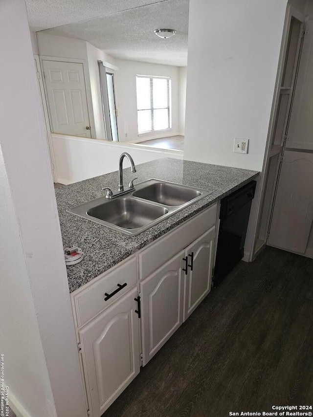 kitchen featuring dark hardwood / wood-style flooring, white cabinets, sink, a textured ceiling, and black dishwasher