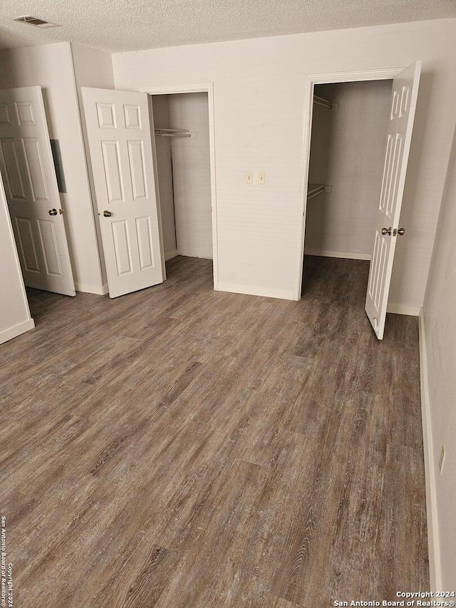 unfurnished bedroom with dark hardwood / wood-style floors and a textured ceiling