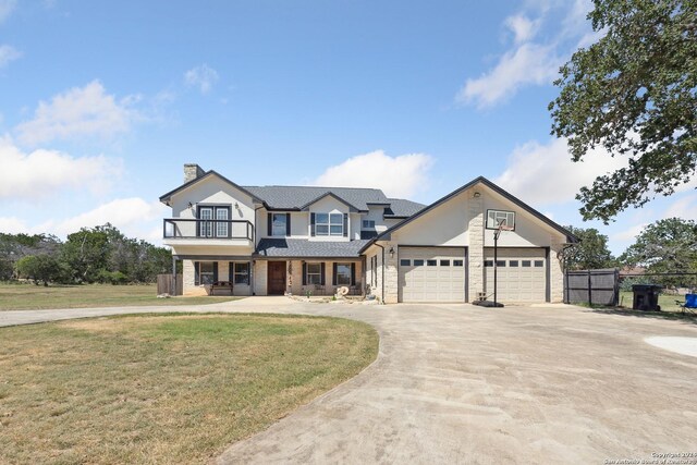 view of front of home featuring a chimney, concrete driveway, a front yard, a balcony, and a garage