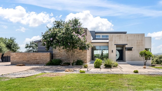 modern home featuring stone siding and a front yard