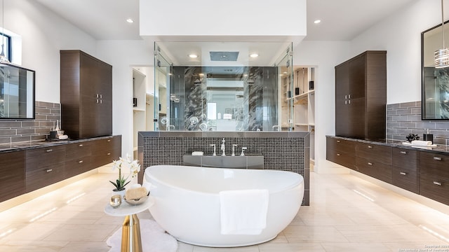 bathroom with tile walls, a tub to relax in, vanity, and tile patterned floors