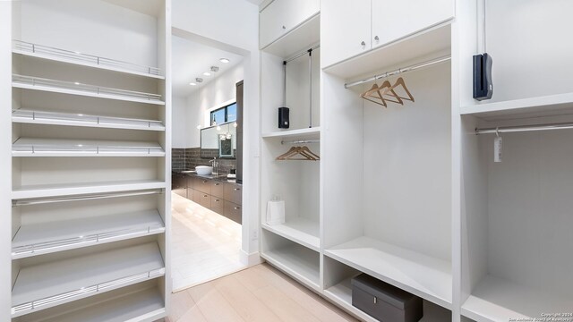 spacious closet with sink and light hardwood / wood-style flooring