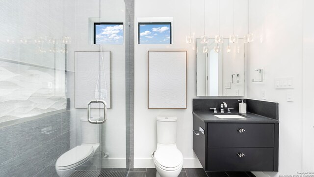 bathroom with tile walls, toilet, vanity, and tile patterned floors