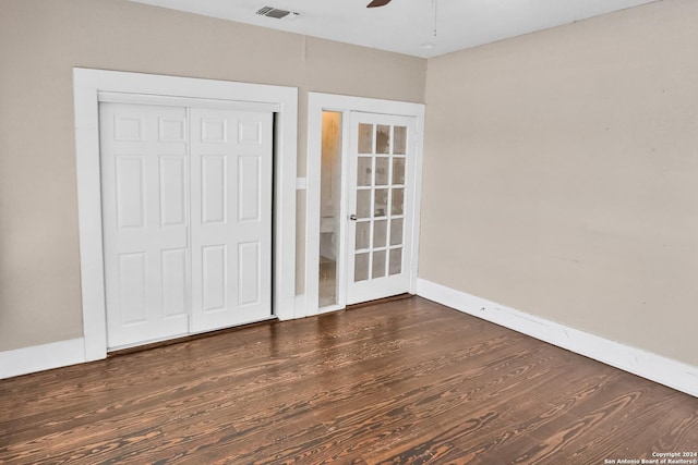 unfurnished bedroom with a closet, visible vents, dark wood-type flooring, ceiling fan, and baseboards