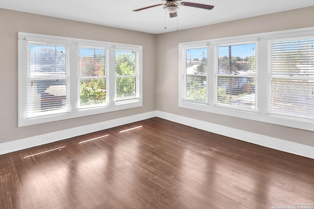 empty room featuring ceiling fan, baseboards, and dark wood finished floors