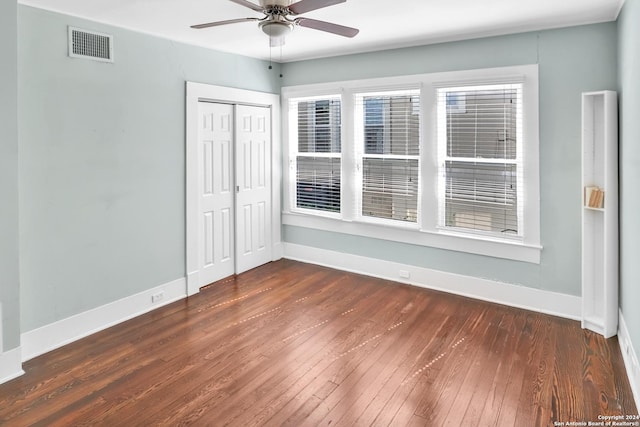 empty room featuring a ceiling fan, baseboards, visible vents, and dark wood-type flooring