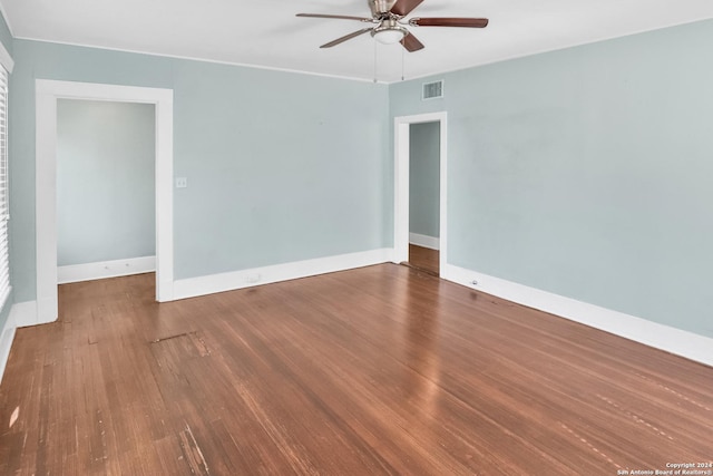 spare room featuring dark wood-style flooring, visible vents, ceiling fan, and baseboards