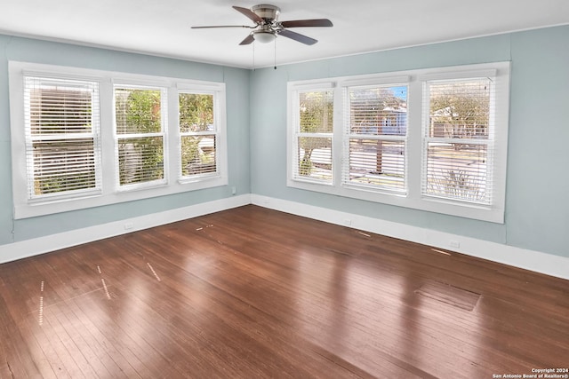 spare room with plenty of natural light, wood finished floors, a ceiling fan, and baseboards