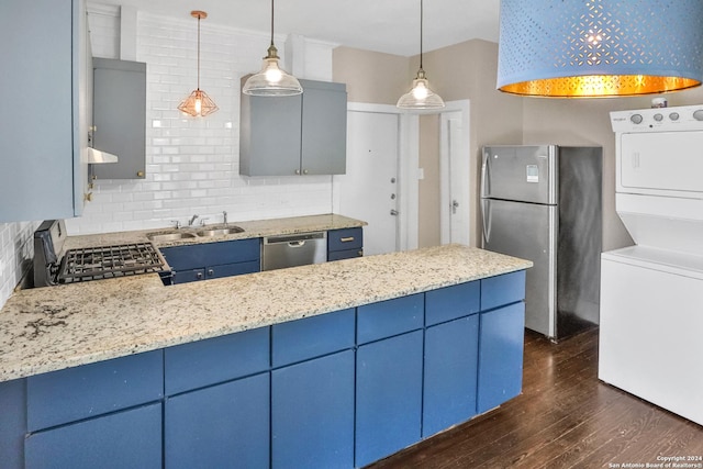 kitchen featuring appliances with stainless steel finishes, stacked washer and dryer, blue cabinets, and hanging light fixtures