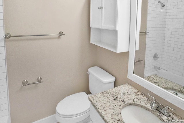 bathroom featuring tiled shower, vanity, toilet, and baseboards