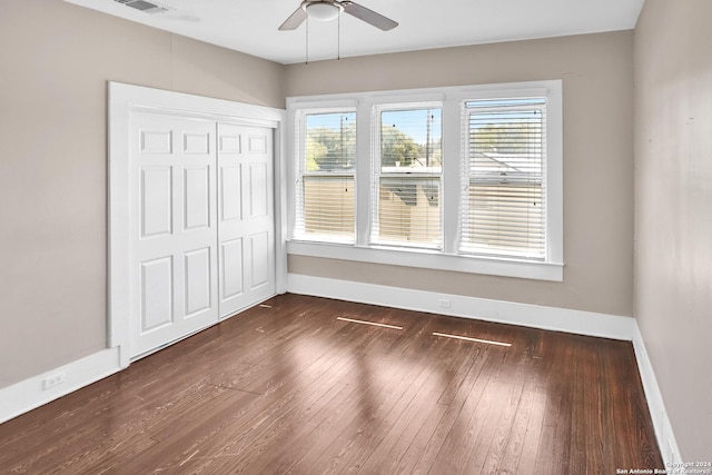 spare room with a ceiling fan, visible vents, baseboards, and dark wood-style flooring