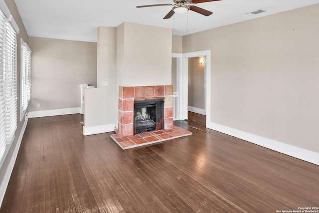 unfurnished living room featuring baseboards, visible vents, a ceiling fan, a tile fireplace, and dark wood-style floors