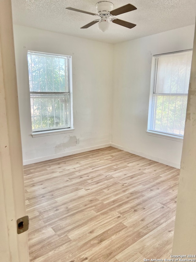 unfurnished room with a wealth of natural light, light hardwood / wood-style flooring, and ceiling fan