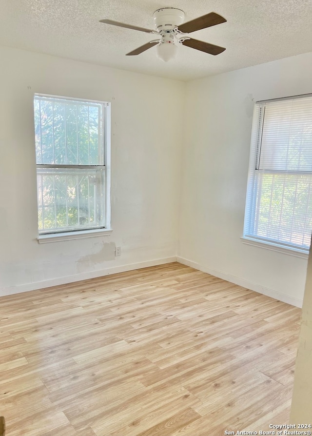 unfurnished room featuring a textured ceiling, ceiling fan, and light wood-type flooring