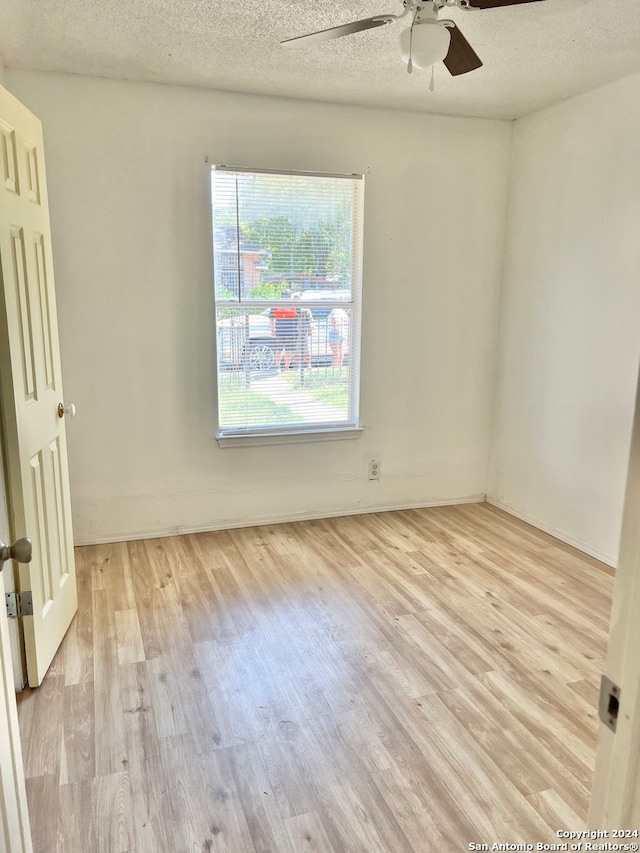 empty room featuring ceiling fan, light wood-type flooring, and a textured ceiling