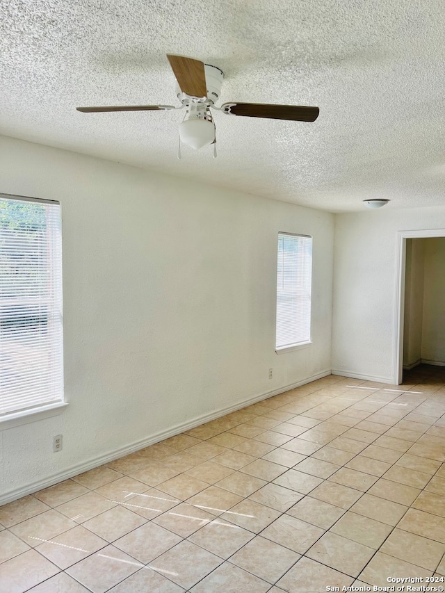 tiled empty room featuring a textured ceiling and ceiling fan