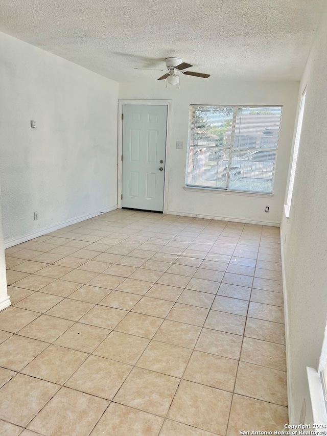 unfurnished room with light tile patterned floors, ceiling fan, and a textured ceiling