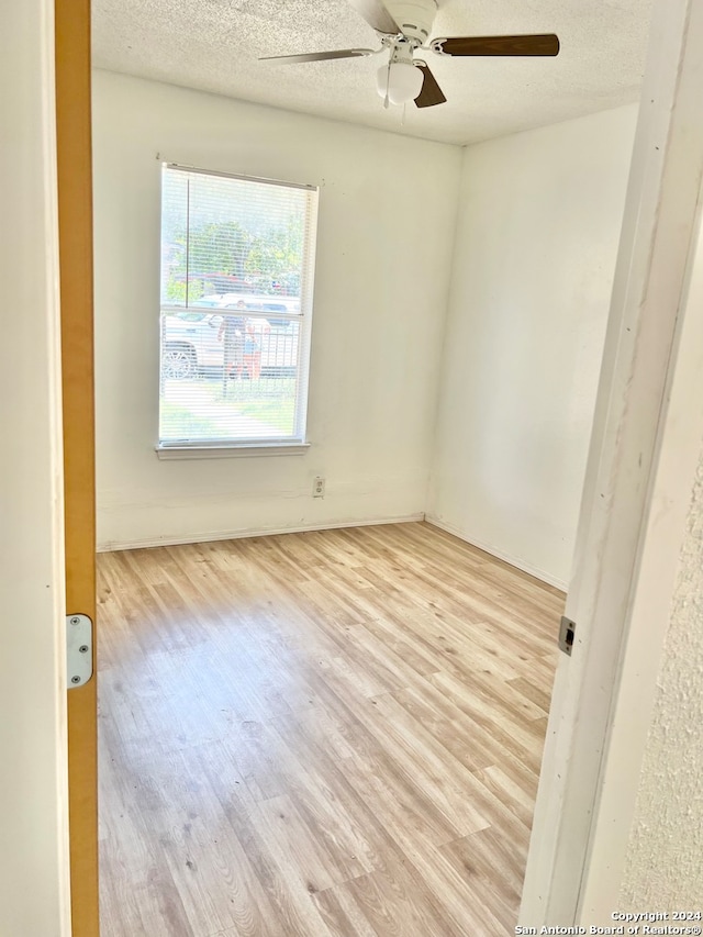 empty room featuring light wood-type flooring, ceiling fan, and a textured ceiling