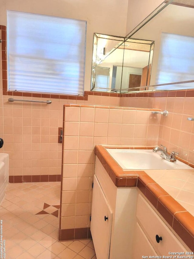 bathroom featuring tile walls, tile patterned flooring, vanity, and tasteful backsplash