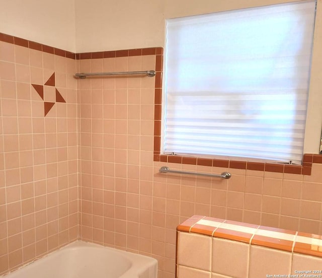 bathroom featuring tiled shower / bath and tile walls