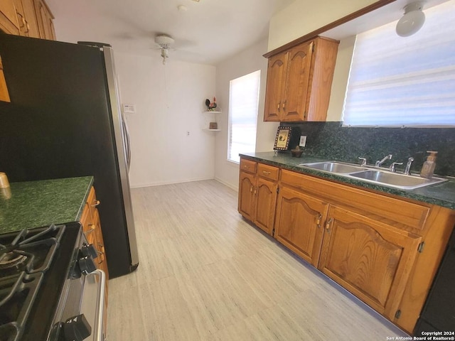 kitchen featuring sink, black refrigerator, decorative backsplash, and stove