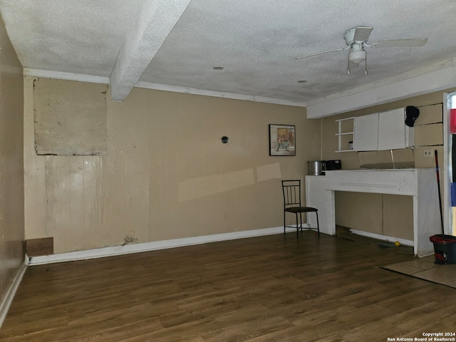 unfurnished living room featuring ceiling fan, wood-type flooring, a textured ceiling, and beamed ceiling