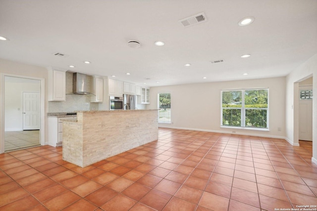 kitchen with light tile patterned floors, stainless steel appliances, visible vents, white cabinets, and wall chimney exhaust hood