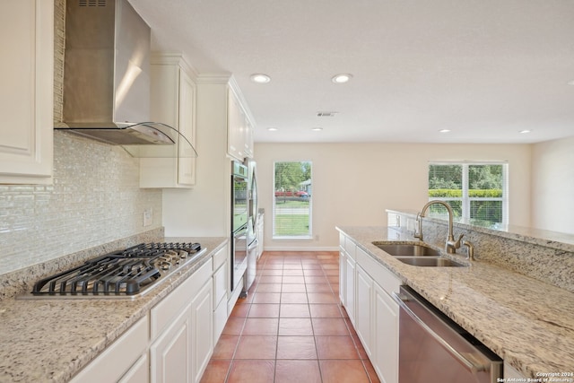 kitchen featuring sink, stainless steel appliances, wall chimney range hood, and white cabinets