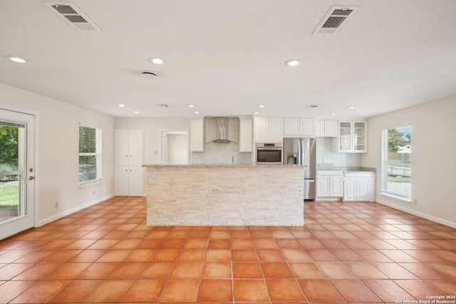 kitchen with light tile patterned floors, appliances with stainless steel finishes, decorative backsplash, and wall chimney range hood