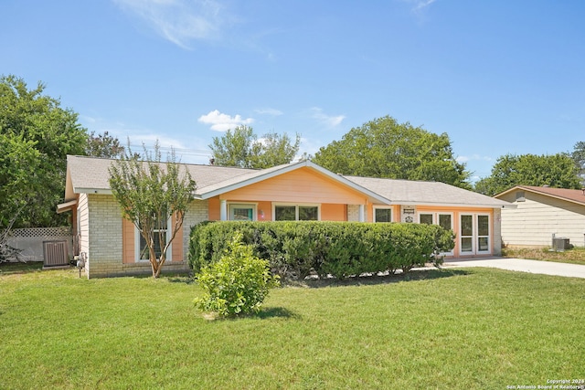 ranch-style house featuring a front lawn and central AC