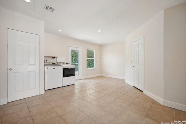 empty room featuring light tile patterned floors, baseboards, visible vents, washing machine and clothes dryer, and recessed lighting