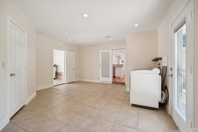 clothes washing area with washer / clothes dryer, light tile patterned flooring, and a healthy amount of sunlight