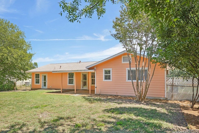 rear view of house with fence and a lawn