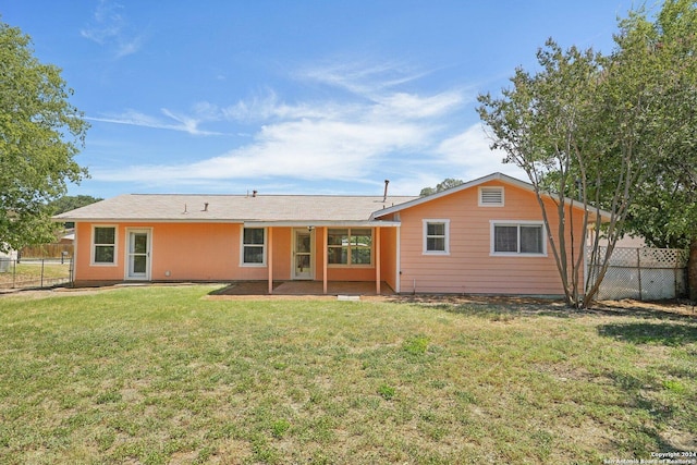 rear view of property featuring a yard, a patio area, and fence