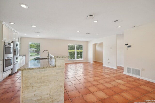 kitchen featuring a wealth of natural light, white cabinetry, light tile patterned floors, and sink