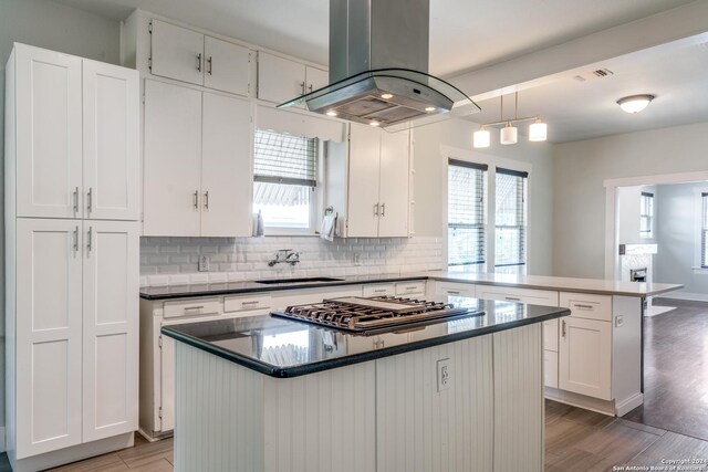 kitchen featuring island range hood, kitchen peninsula, a center island, and wood-type flooring