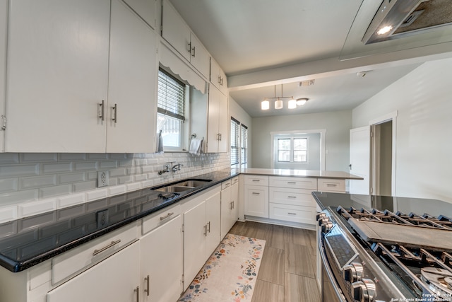 kitchen with tasteful backsplash, range with two ovens, white cabinetry, sink, and kitchen peninsula