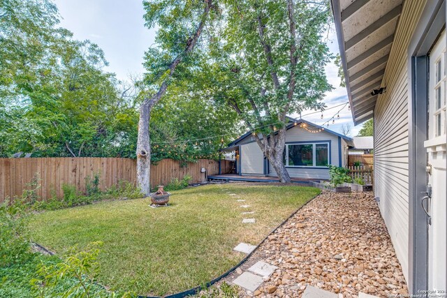 view of yard with a fenced backyard, an outdoor structure, and a fire pit