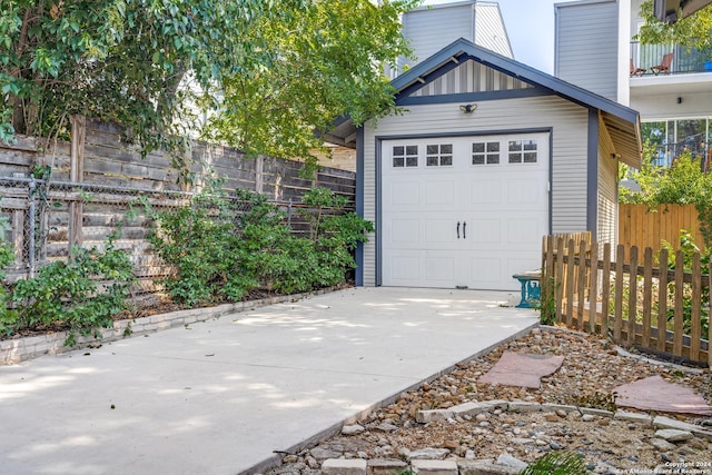 garage featuring concrete driveway and fence