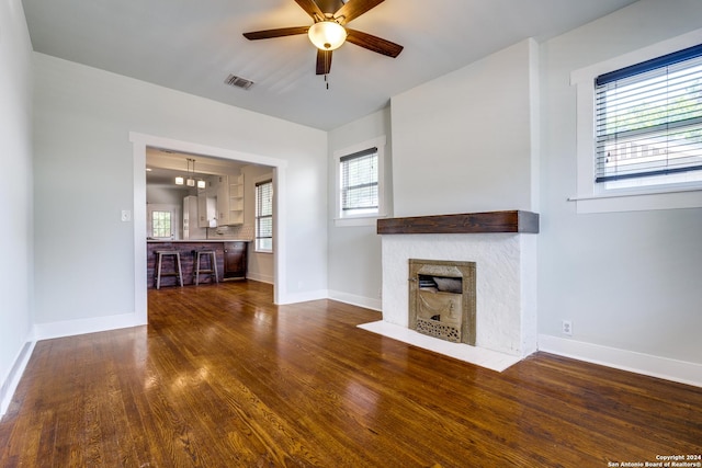 unfurnished living room featuring dark wood-style floors, a fireplace with flush hearth, baseboards, and ceiling fan