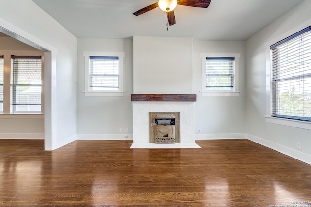 unfurnished living room featuring a fireplace with flush hearth, dark wood finished floors, and plenty of natural light