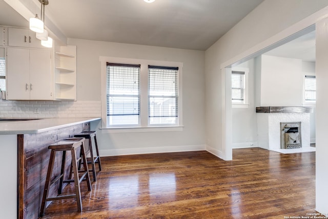 kitchen with a breakfast bar, white cabinets, hanging light fixtures, light countertops, and open shelves